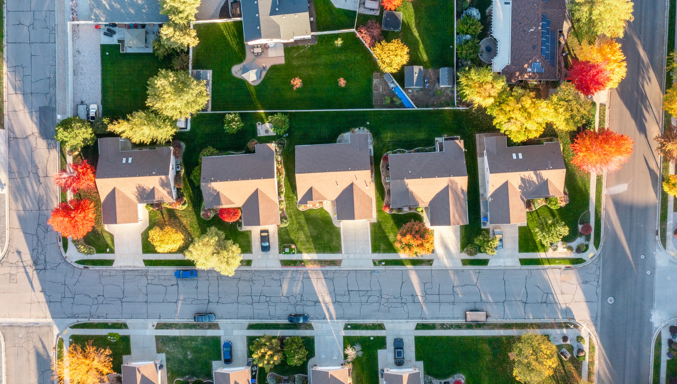 Aerial view of a northern Utah neighborhood in fall — homes and landscaped yards